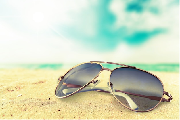 Gafas de sol en el fondo de la playa de arena