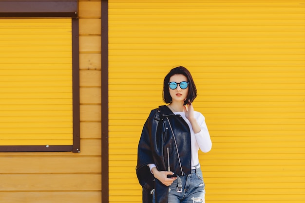 Gafas de sol hermosas de la muchacha en fondo amarillo brillante