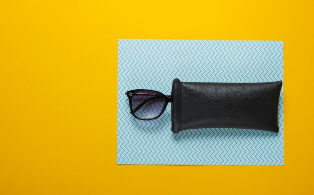 Gafas de sol de moda en una funda protectora sobre una mesa de cartón. Vista superior