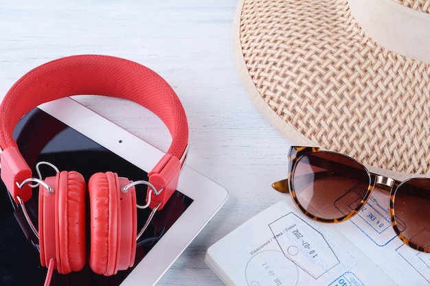 Gafas de sol, pasaporte, auriculares, tableta y un sombrero.