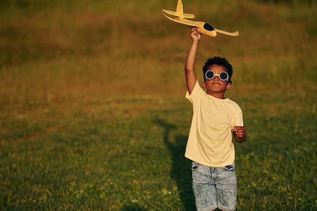 Gafas de sol piloto de estilo retro El niño afroamericano se divierte en el campo durante el día de verano