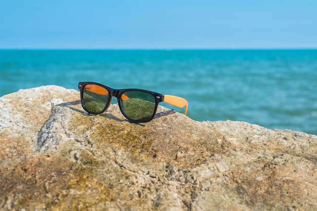 Gafas de sol en las rocas con un fondo del mar