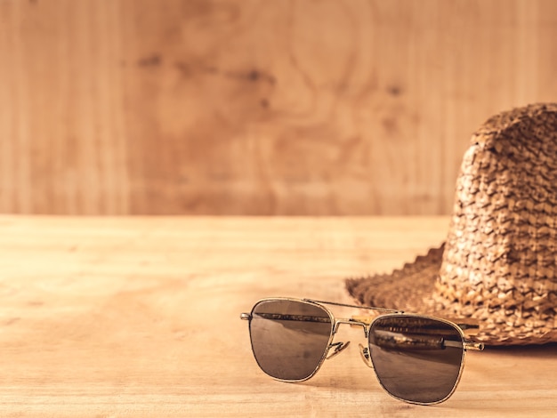 Gafas de sol y sombrero en la mesa de madera