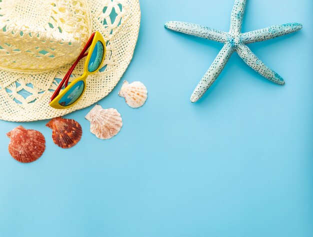 gafas de sol, sombrero de paja, conchas marinas, estrellas de mar sobre un fondo azul