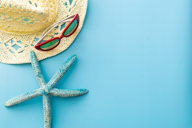 gafas de sol, sombrero de paja, estrella de mar sobre un fondo azul