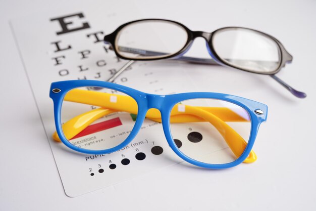 Gafas en la tabla de examen ocular para probar la precisión de la vista de la lectura