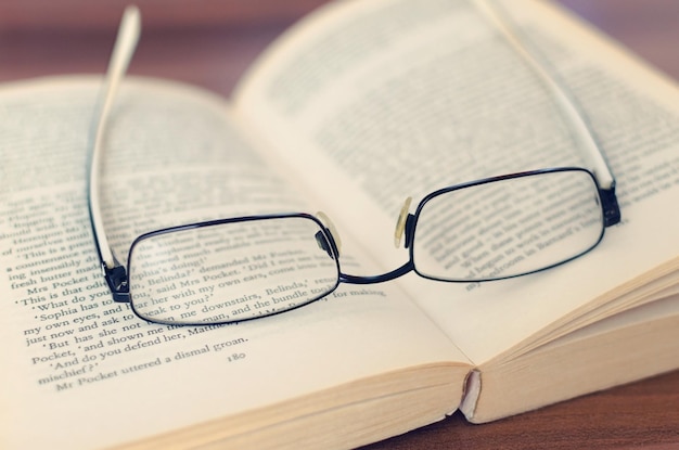 Gafas viejas y un libro en el escritorio de la biblioteca.