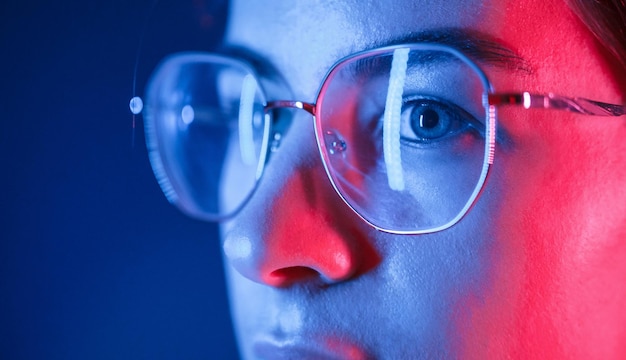 En gafas Vista de cerca Mujer hermosa joven está adentro en el estudio iluminado por luz de neón