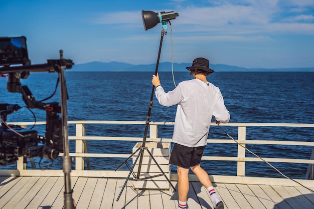 Gaffer ou o eletricista-chefe em uma unidade de produção de cinema ou televisão monta as luzes e o suporte de luz em uma filmagem comercial