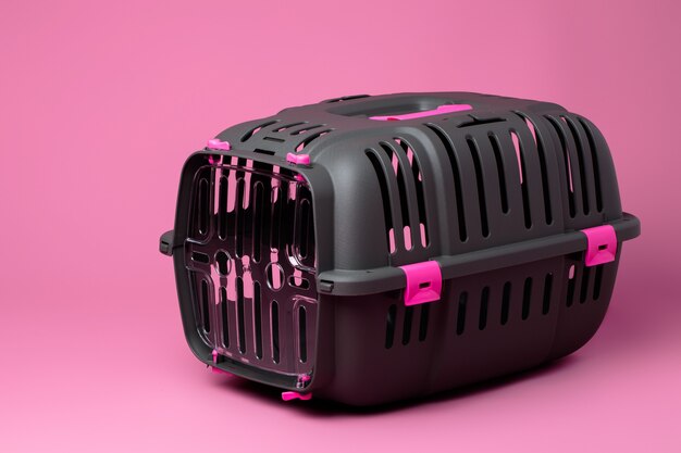 Gaiola de transporte de animais em fundo rosa pastel