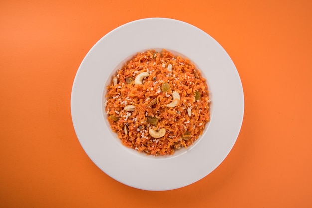 Gajar halwa é um pudim de sobremesa doce à base de cenoura da índia. guarnecido com castanhas de caju, amêndoas e servido em uma tigela sobre um fundo colorido de madeira