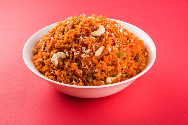 Gajar Halwa es un pudín de postre dulce a base de zanahoria de la India. Adornado con anacardos, almendras y servido en un recipiente sobre fondo de madera colorida