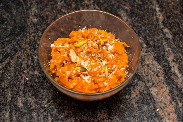 Foto gajar halwa ou halva de cenoura com nozes, amêndoa, pistache, leite khoya e óleo, servido em prato isolado na vista superior de fundo de bangladesh e comida indiana