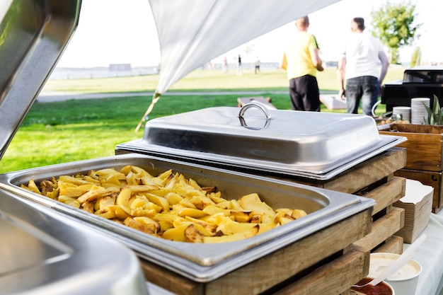 Gajos de patata en un calentador de alimentos en una fiesta de verano Foto horizontal