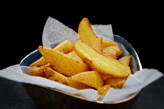 Gajos de patata frita en papel sobre un negro