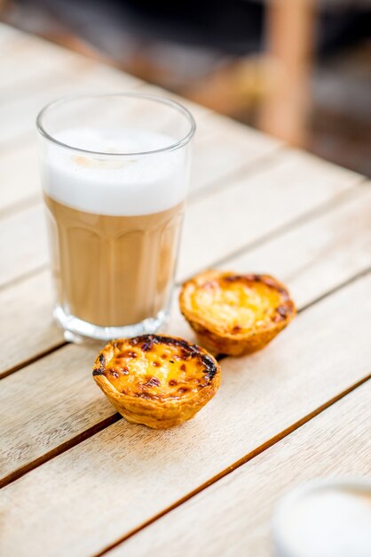 Galao de café portugués con postre dulce pastel de Nata en la mesa al aire libre