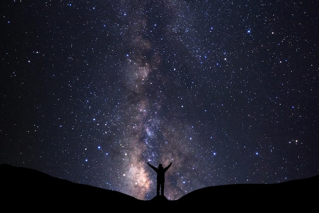 Galaxia de la vía láctea con estrellas y silueta de un hombre feliz de pie