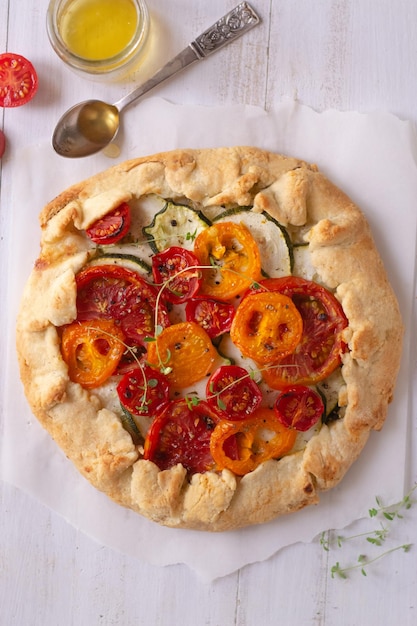 Galette de calabacín y tomate sobre mesa de madera blanca