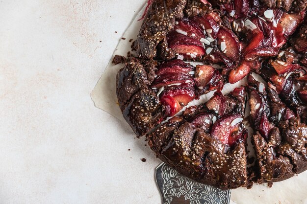 Galette caseira ou torta aberta com chocolate, ameixa e amêndoa sobre fundo claro de concreto. vista do topo.