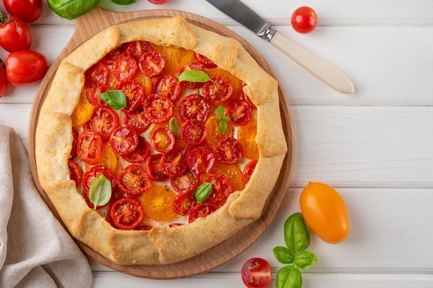 Galette de tomate ou torta com queijo e ervas em um fundo branco de madeira Prato vegetariano