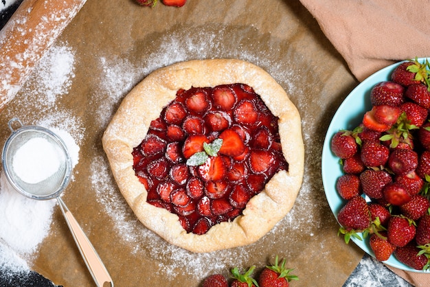 Galette de fresas caseras con fresas frescas maduras en un oscuro.