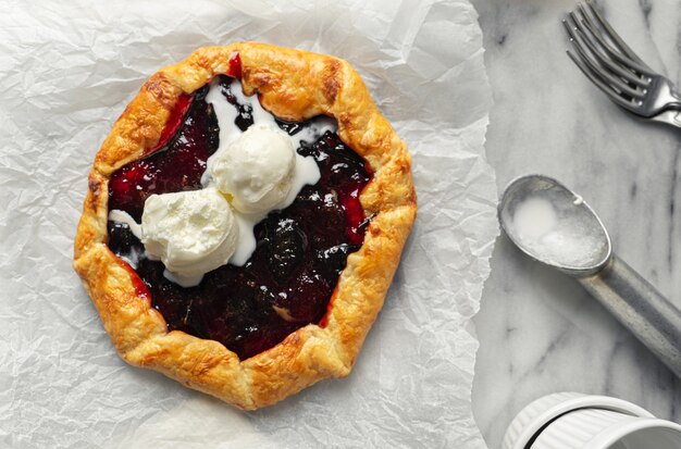 Galette de mermelada de ciruela sobre superficie de mármol servida con bola de helado