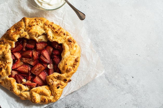 Galette de verano de fresa con hojaldre y hojuelas de almendras sobre fondo gris Copiar espacio