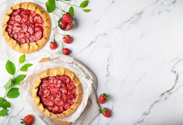 Galettes caseros frescos con fresas sobre fondo de mármol blanco. Vista superior. Espacio para texto.