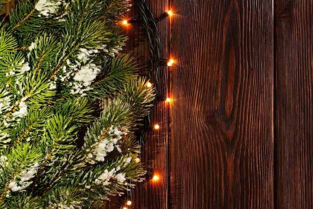 Galho de árvore de natal e luzes na madeira
