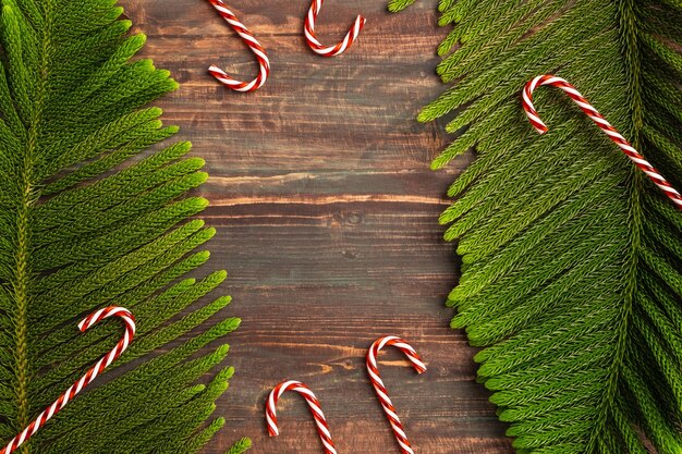 Galho de pinheiro de Natal e bengala de doce vermelho no fundo da mesa de madeira