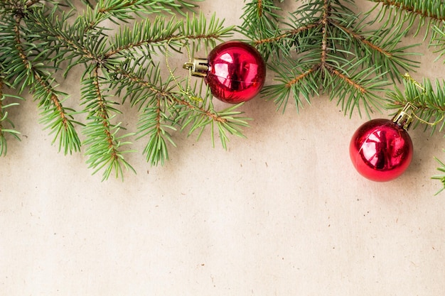 Galhos de árvore do abeto decorados com bolas vermelhas de Natal como borda em um quadro de fundo rústico de férias com espaço de cópia