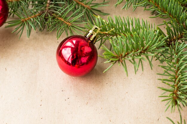 Galhos de árvore do abeto decorados com bolas vermelhas de Natal como borda em um quadro de fundo rústico de férias com espaço de cópia