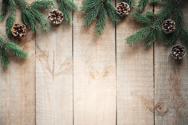 Galhos de árvores de Natal com pinhas em fundo de madeira