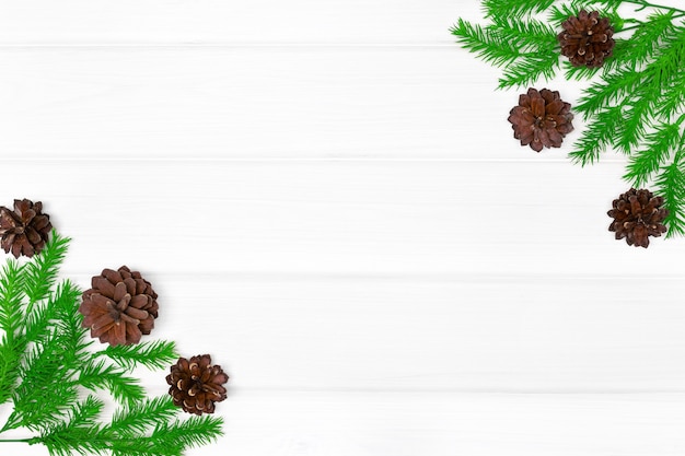 Galhos de árvores de Natal com pinhas na mesa de madeira branca. Copie o espaço