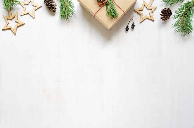 Galhos de árvores de Natal, cones e acessórios de Natal de madeira em um fundo branco de madeira