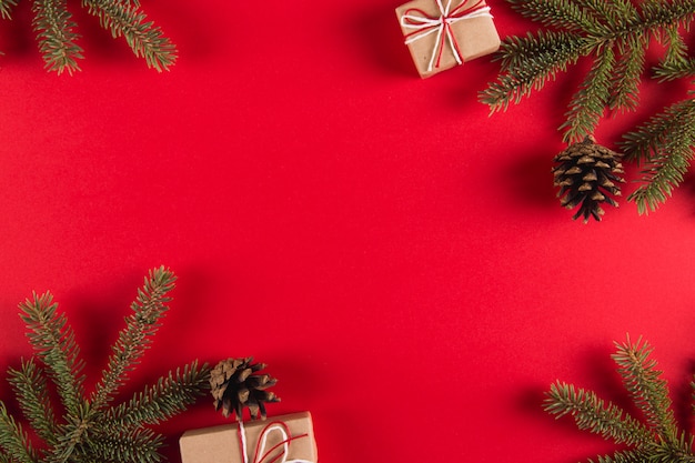 Galhos de árvores de Natal, presentes e pinhas em um vermelho, Natal, cartão copyspace.