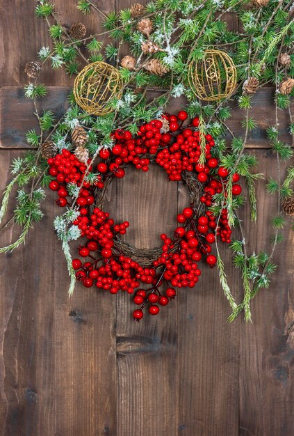 Galhos de árvores de Natal verdes e grinaldas de bagas vermelhas sobre fundo de madeira rústico