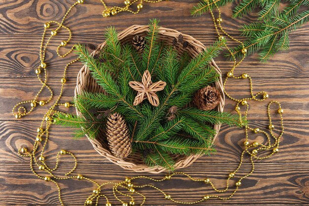 Galhos de pinheiro com cones e uma estrela em uma cesta sobre um fundo de madeira Natal e ano novo