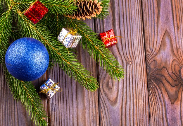 Galhos de uma árvore de Natal decorada com bola azul e brinquedos de seda em uma mesa de madeira