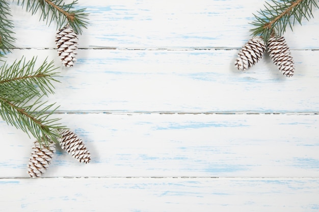 Galhos verdes de uma árvore de Natal com cones em um fundo branco de madeira