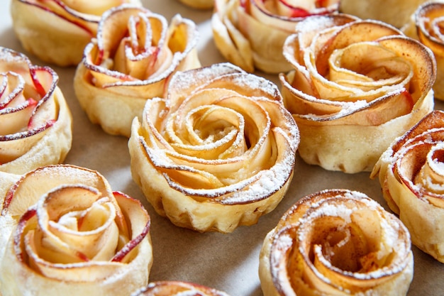 Galleta casera con manzanas en forma de rosa sobre papel para hornear. De cerca