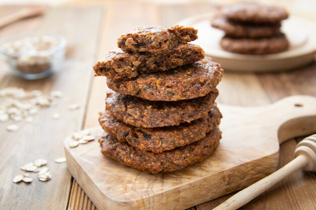 Galleta casera saludable con copos de avena, frutos secos y semillas. Mesa rústica de madera.