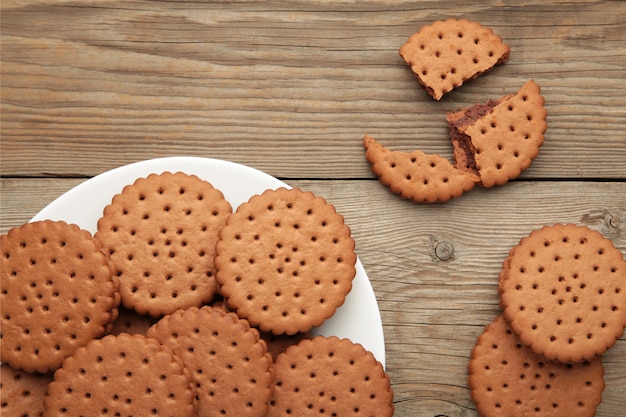 Galleta con chispas de chocolate en un plato blanco sobre fondo de madera gris. Vista superior.