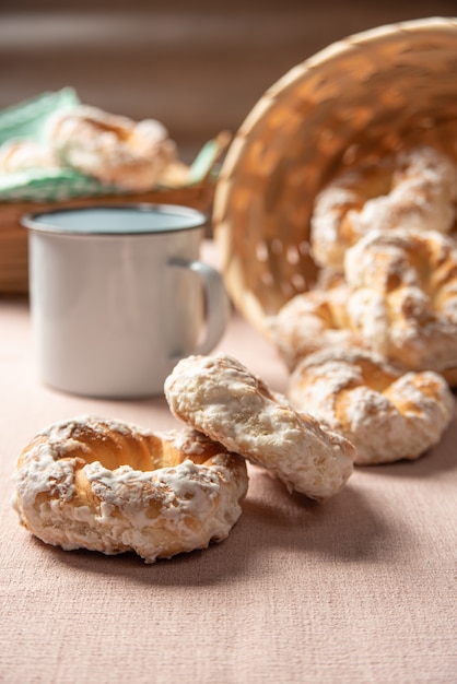 Galleta dulce brasileña y una taza de café sobre una mesa con mantel beige, enfoque selectivo.