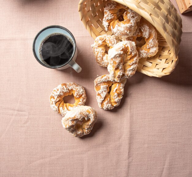 Galleta dulce brasileña y una taza de café sobre una mesa con mantel beige, enfoque selectivo.