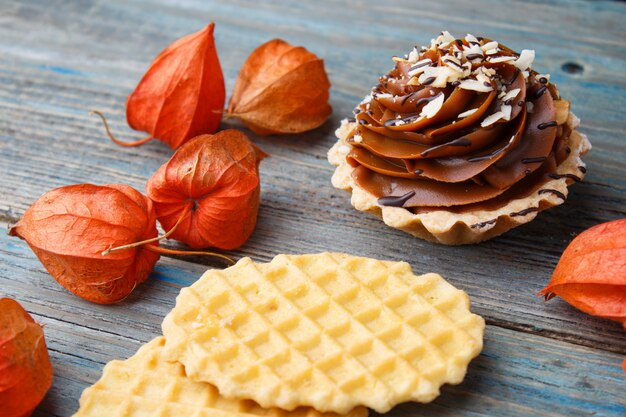 Galleta dulce, pastel con crema y physalis sobre un fondo de madera