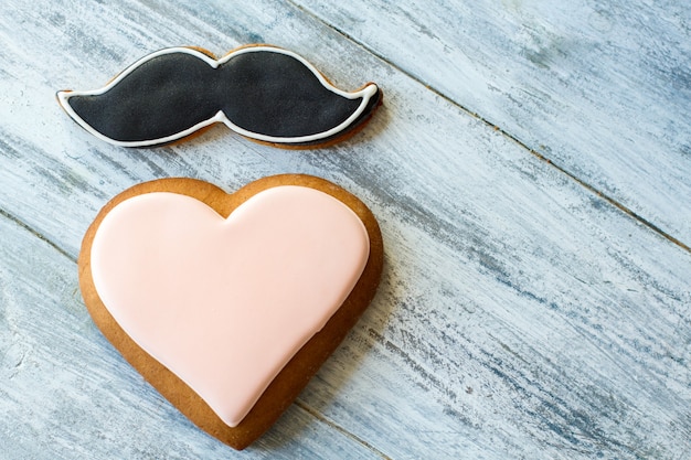 Galleta en forma de corazón. Galleta de bigote con glaseado negro. El caballero envía un saludo a la dama. Sentimientos y modales.