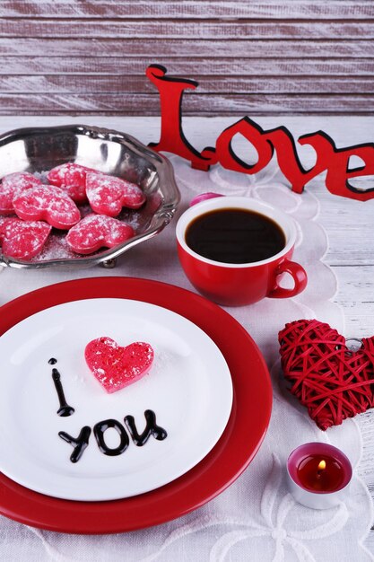 Foto galleta en forma de corazón en un plato con la inscripción te amo en el fondo de la mesa de madera de color