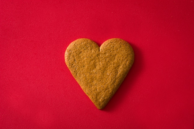 Foto galleta en forma de corazón sobre superficie roja