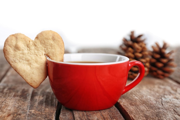 Galleta con forma de corazón en una taza de café en el primer plano de la mesa de madera